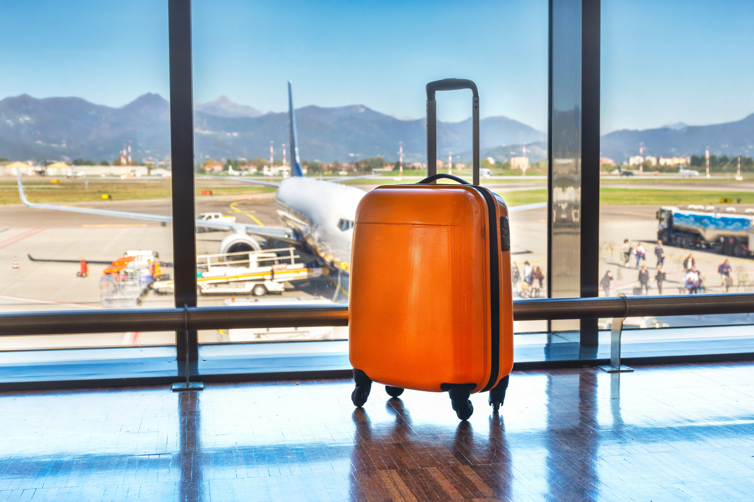 an orange suitcase sits in front of an airport terminal